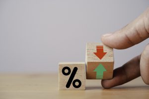 Hand flipping wooden cube block to change between up and down with percentage sign symbol for increase and decrease financial interest rate and business investment growth from dividend concept.